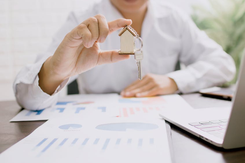 A real estate investor holding a key with a small wooden house model, symbolizing investment apartments in Ajman for high rental yields.