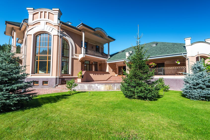Low-maintenance gardening ideas in Ajman – beautifully landscaped villa with lush green lawn, evergreen trees, and minimal upkeep outdoor design.