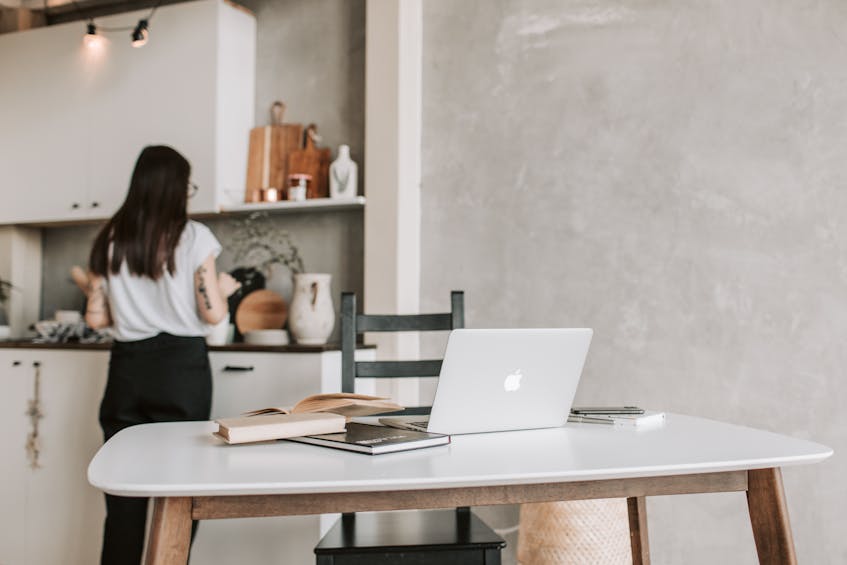 a lady standing in the open kitchen of apartment handle all devices of home through its laptop reflect smart home trends in ajman